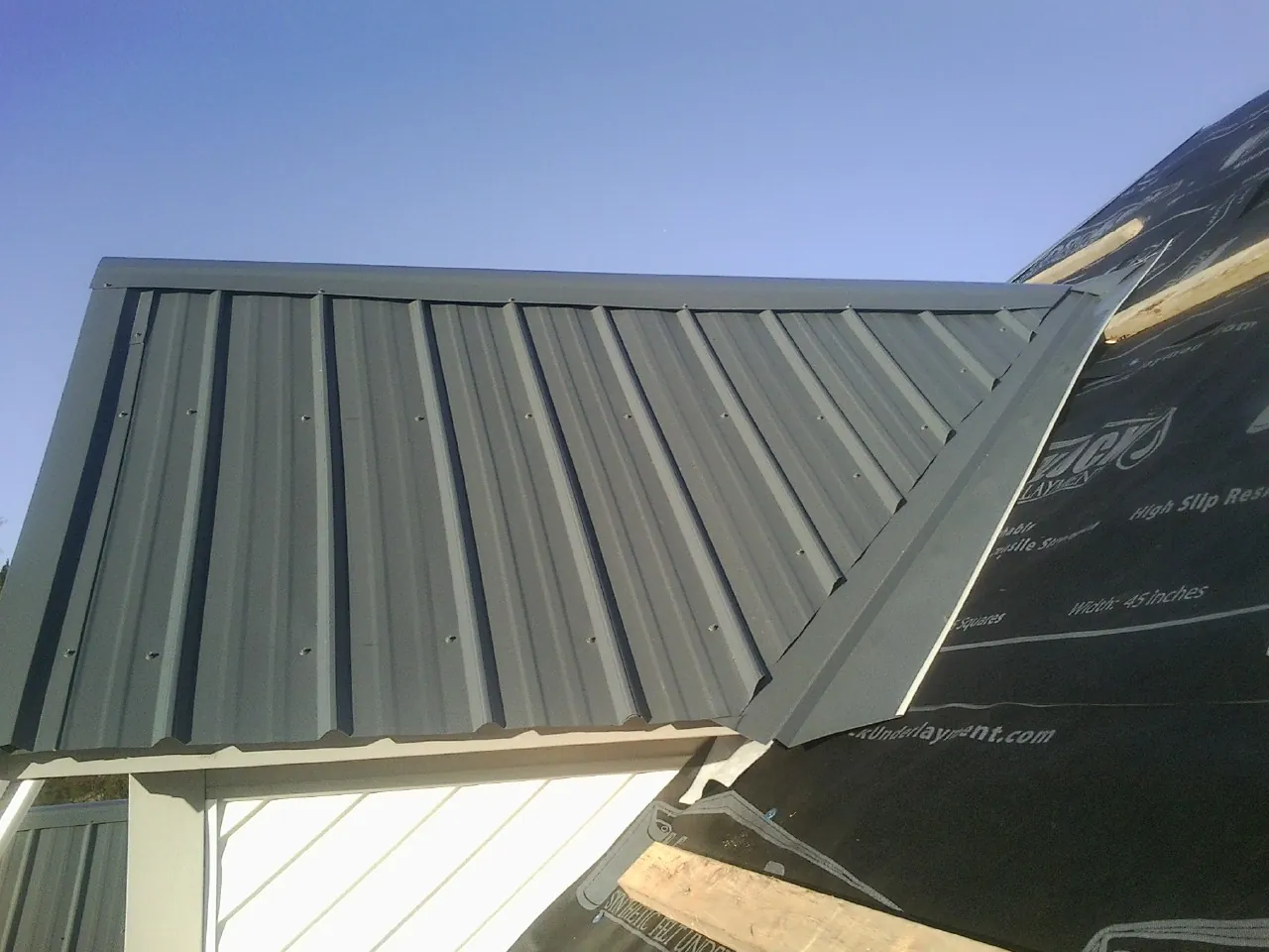 Gray metal roof panels going on over a garage gable in Franklin